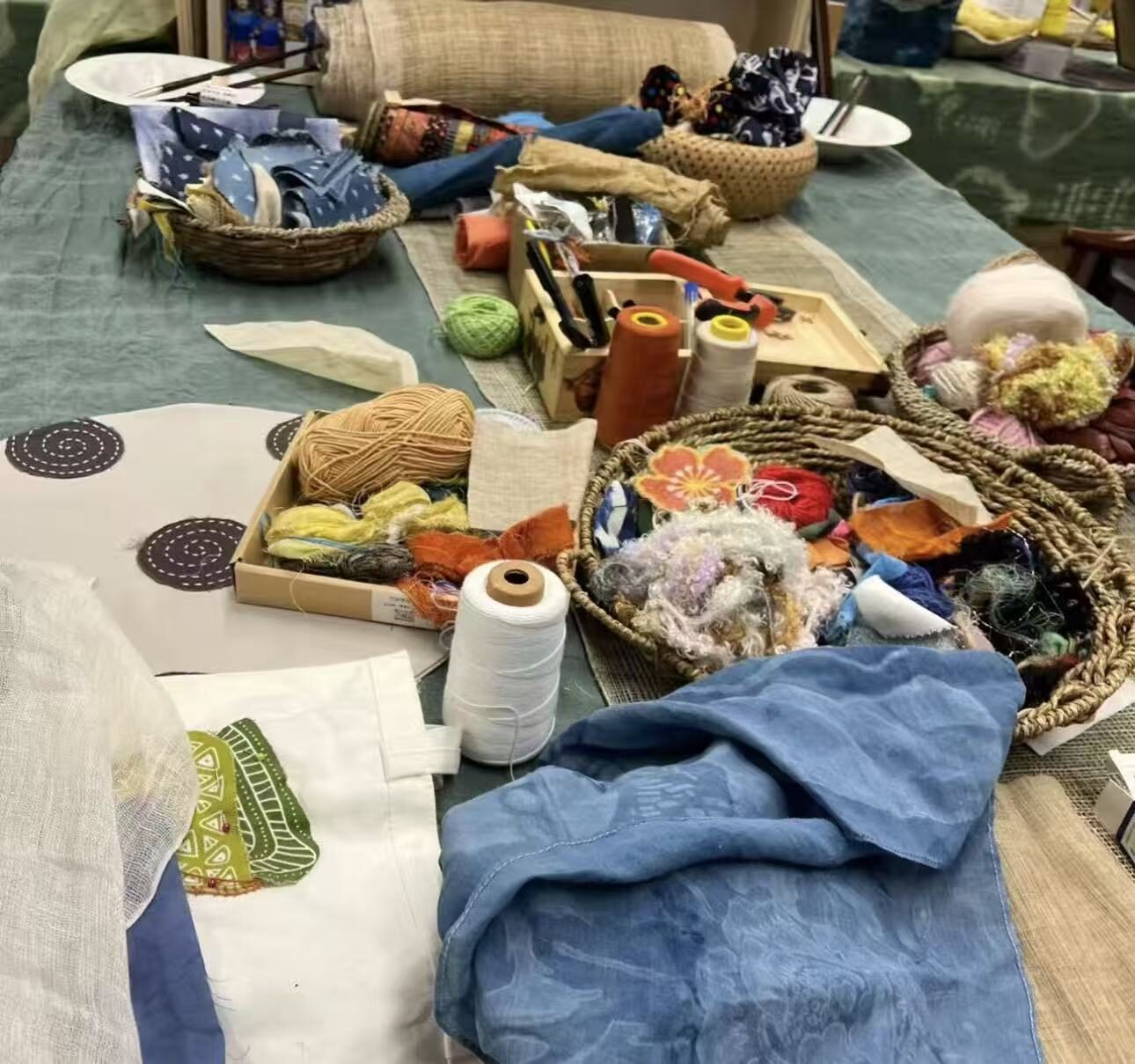 Table with threads, fabrics and baskets of materials
